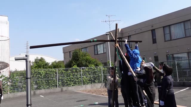 屋外でポールを立てて設営する参加者